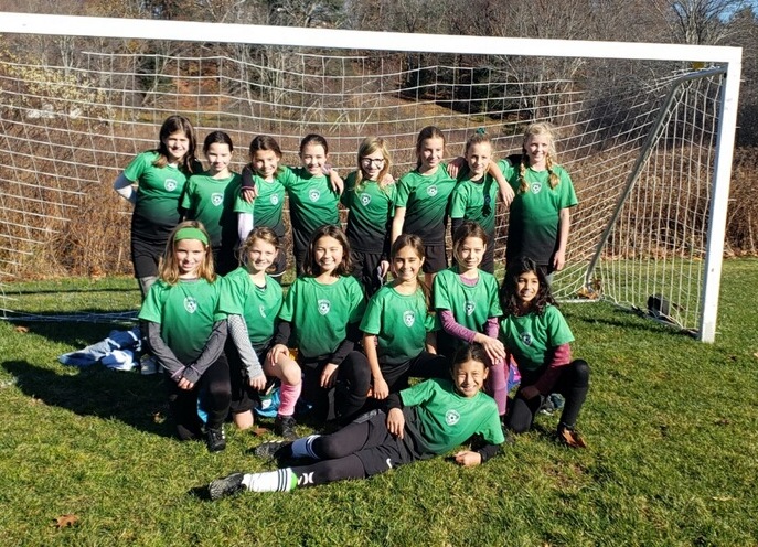 girls team posing in front of goal